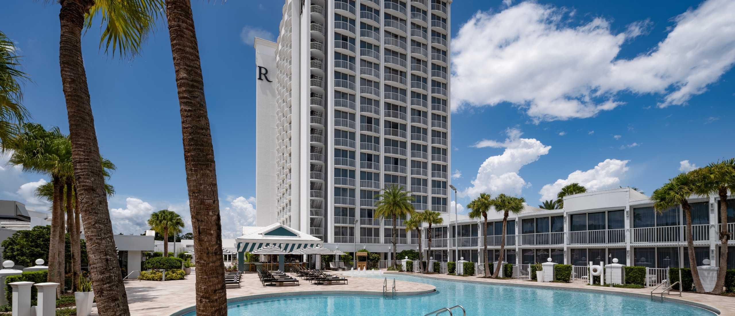Zero-entry resort pool with lounge chairs and palm trees at Renaissance Orlando Resort – Disney Springs® Area